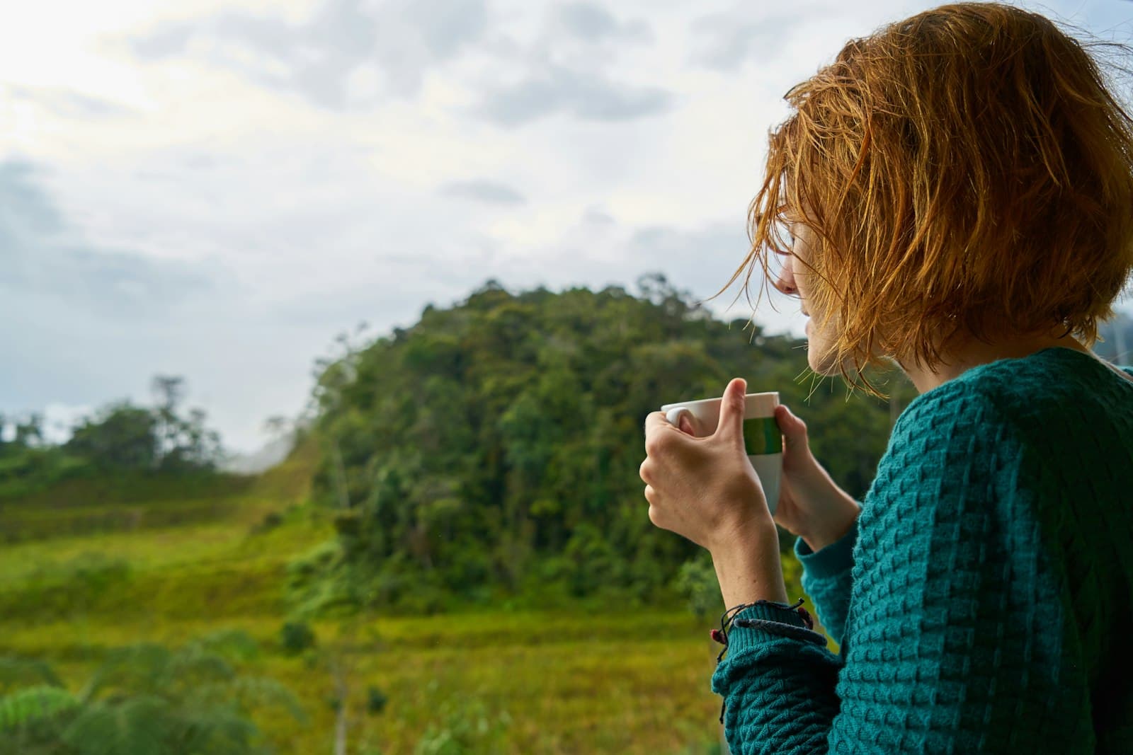 Una persona tomando té tranquilamente al aire libre, con una expresión de serenidad y conexión con el entorno.