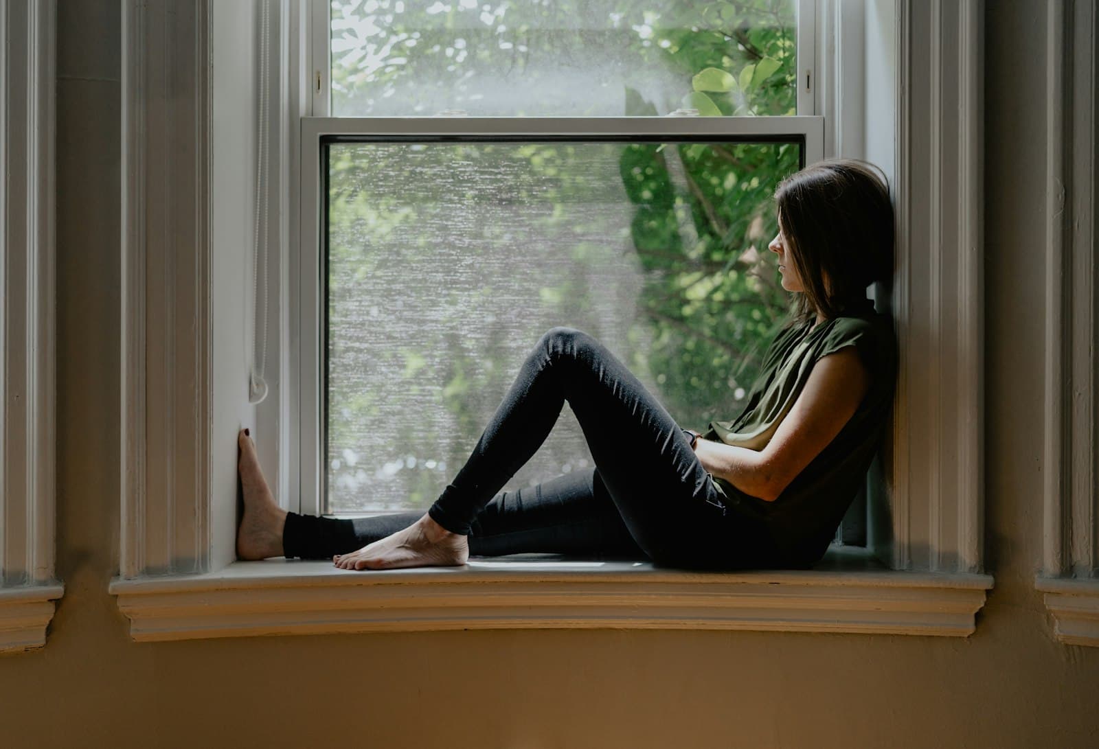 Una persona escribiendo en un diario junto a una ventana con una vista serena