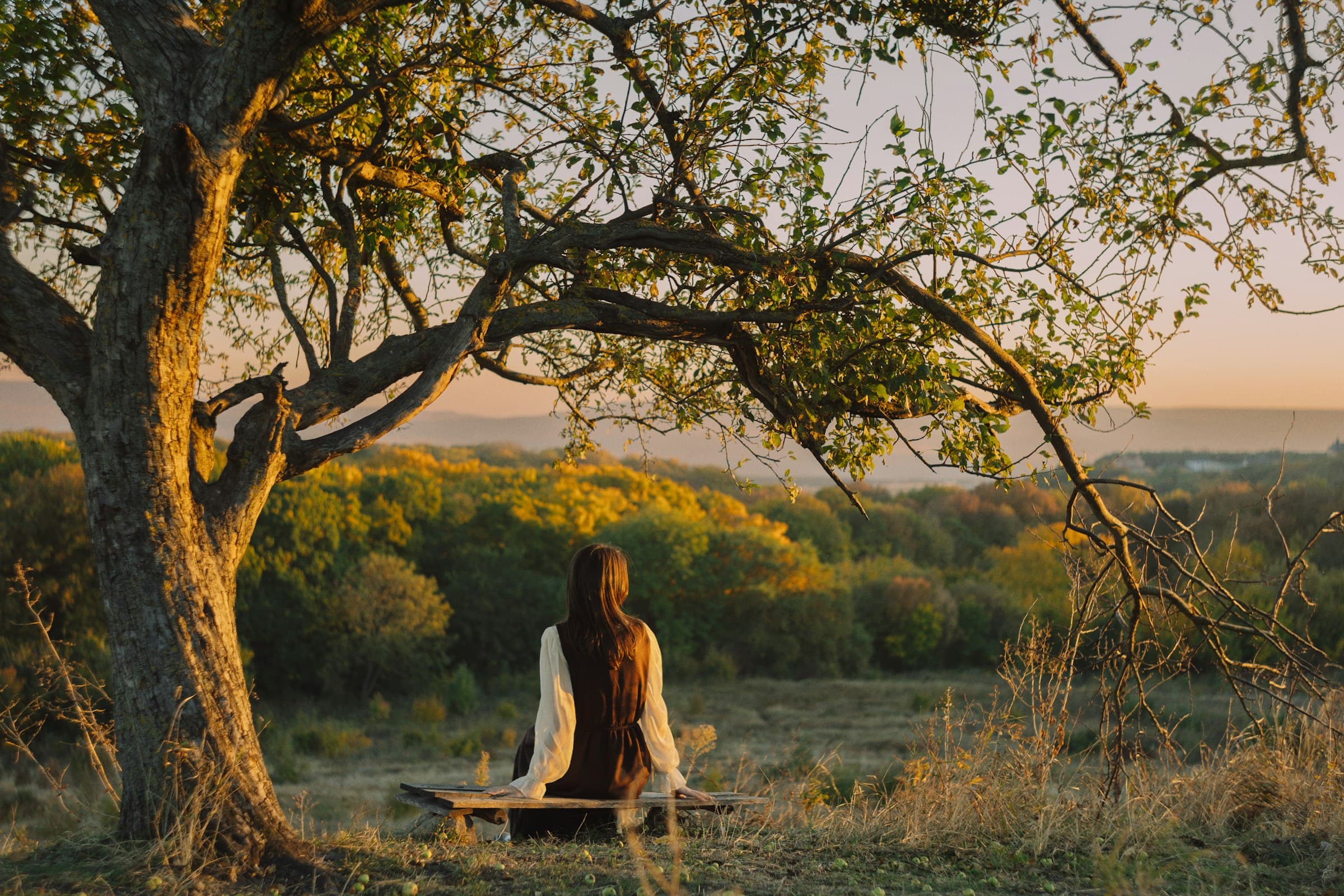A person meditating peacefully at sunrise in a serene mountain landscape.