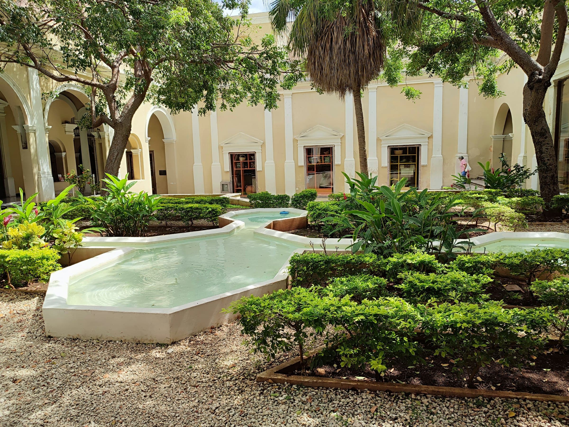 Un patio interior sereno de una hacienda en Mérida, con plantas tropicales y luz suave.