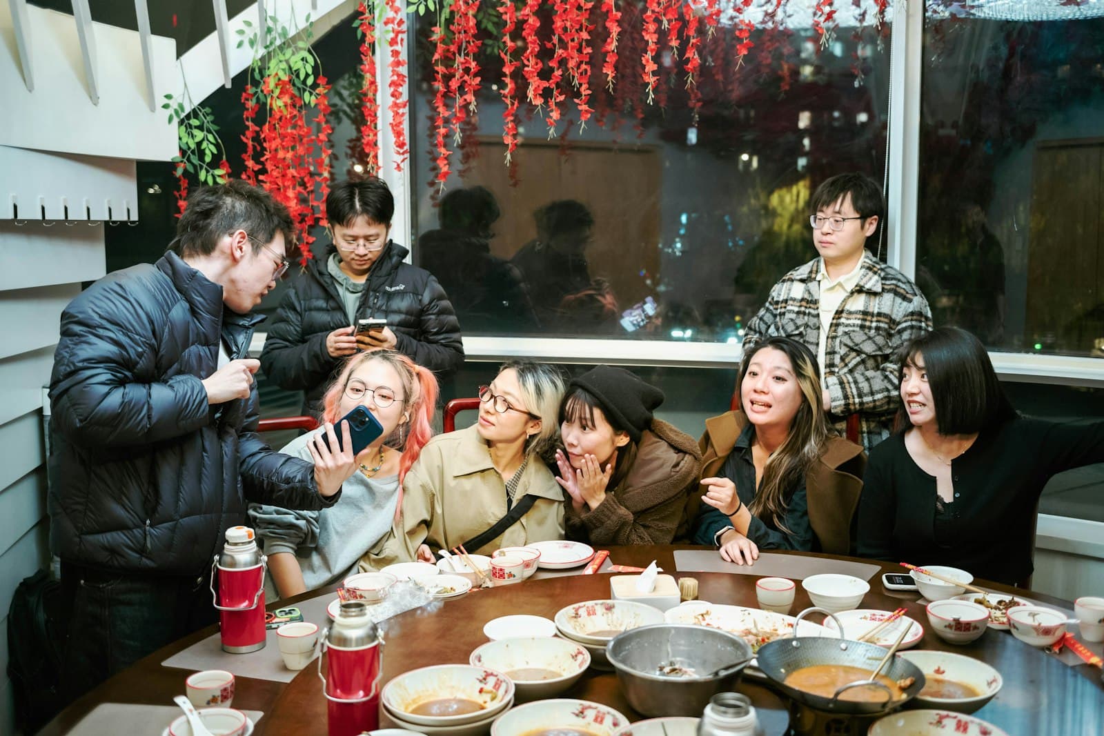Grupo de personas compartiendo una comida y riendo juntas en una mesa comunitaria