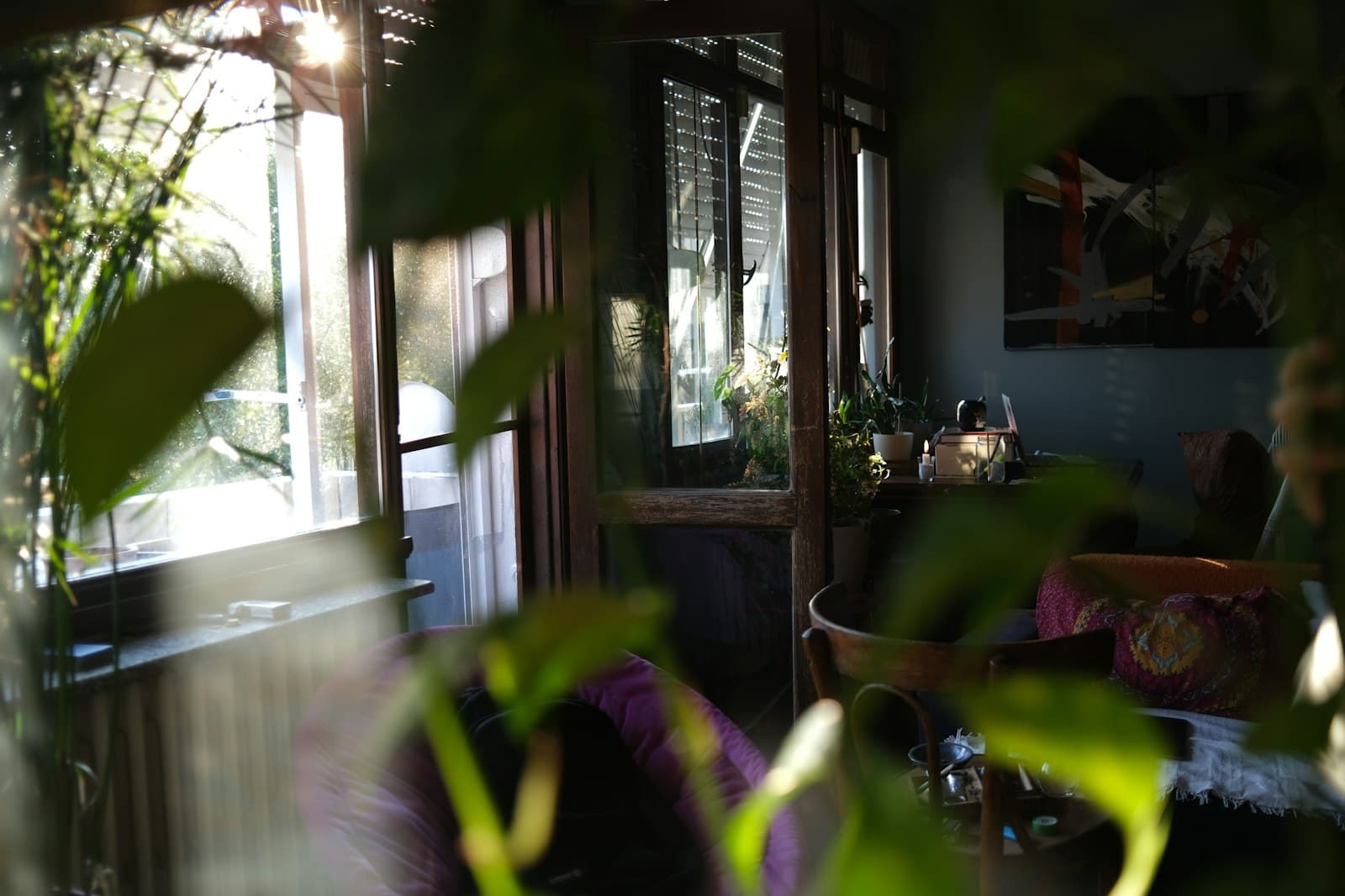 Interior de una casa luminosa con grandes ventanales, plantas y mobiliario minimalista y acogedor.