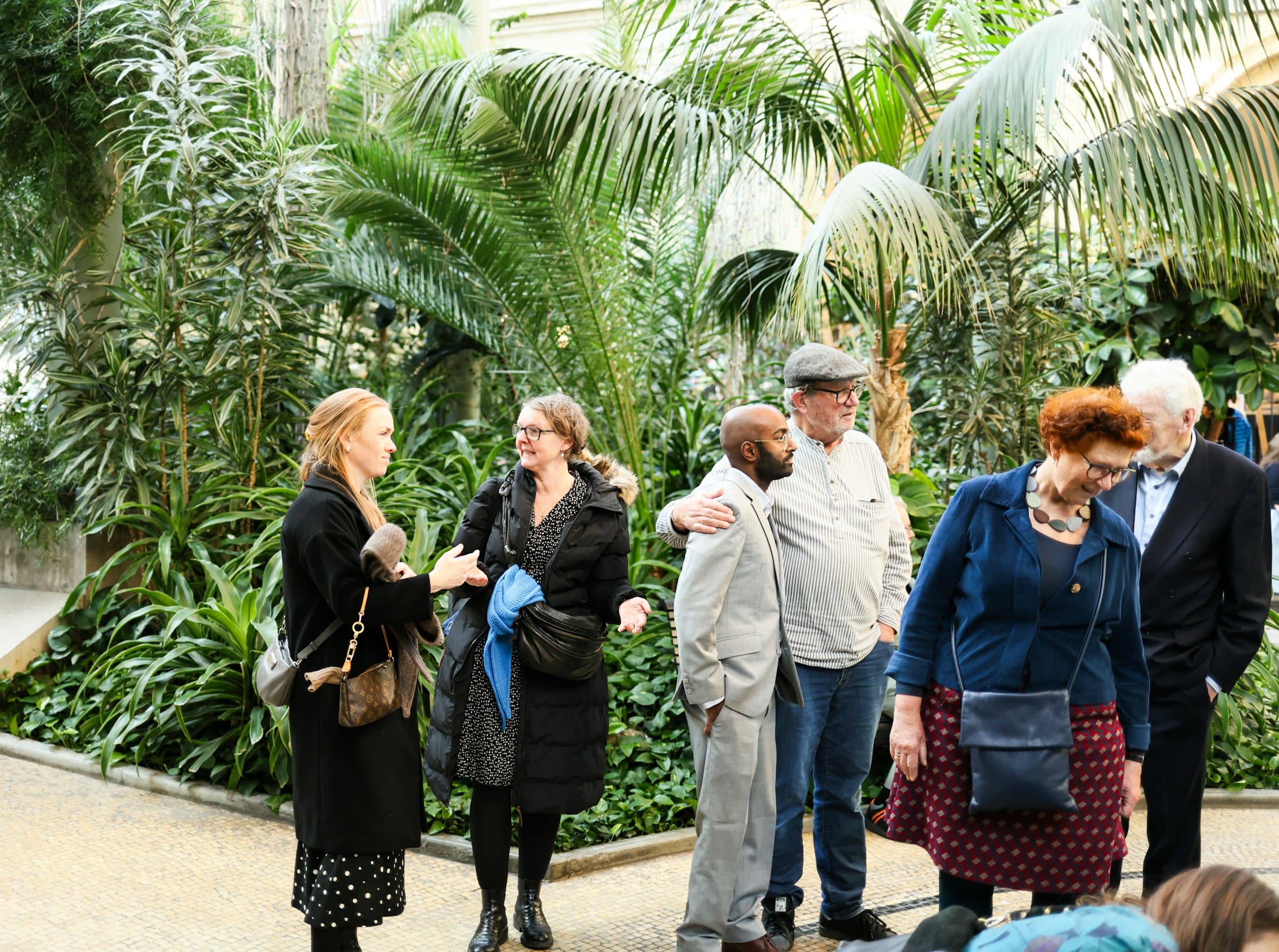 Grupo de personas sonriendo y conversando en un jardín exuberante, simbolizando la comunidad y el bienestar