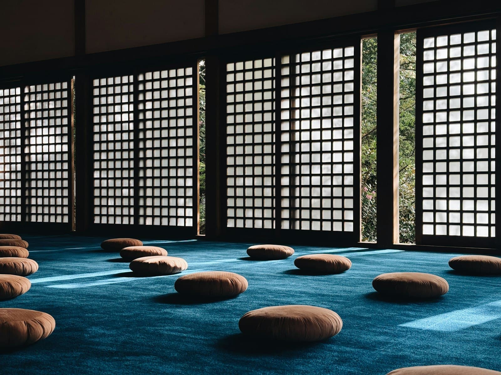 Un espacio sereno para la meditación con abundante luz natural, plantas de interior y elementos de madera clara.