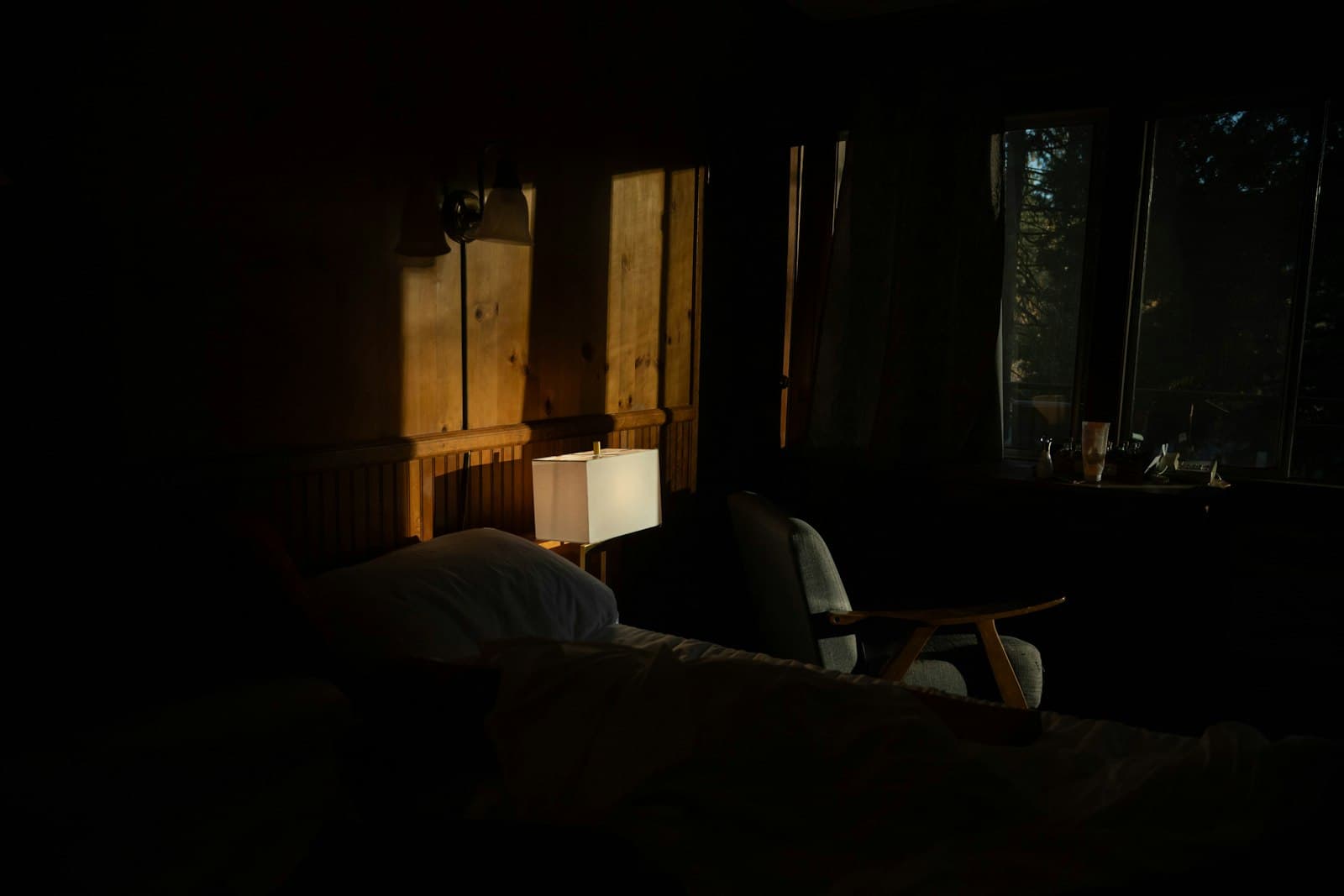 Un dormitorio acogedor y cálido por la noche, con una lámpara de lectura suave y un libro en la mesita de noche, invitando al descanso