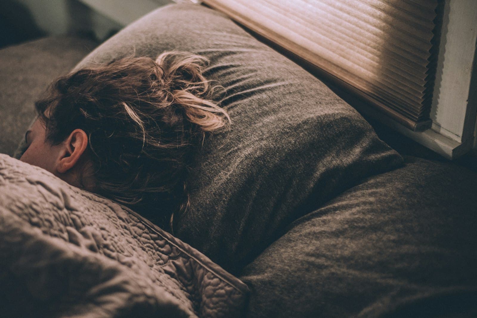 Persona durmiendo plácidamente en una cama limpia y cómoda, transmitiendo serenidad.