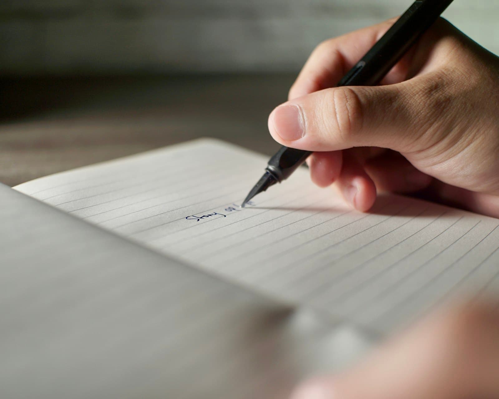 Primer plano de manos escribiendo en un cuaderno con una pluma, concentradas en el acto de la escritura.