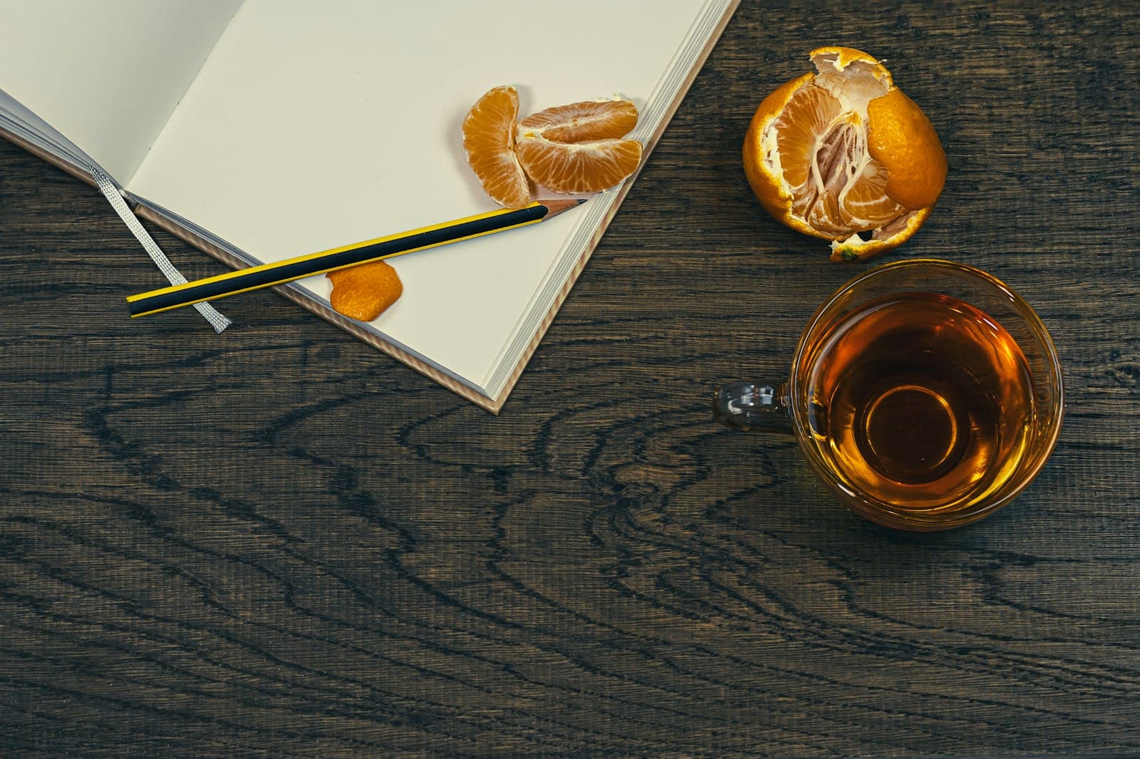 Un cuaderno abierto sobre una mesa de madera, acompañado de una taza de té, creando una atmósfera acogedora.