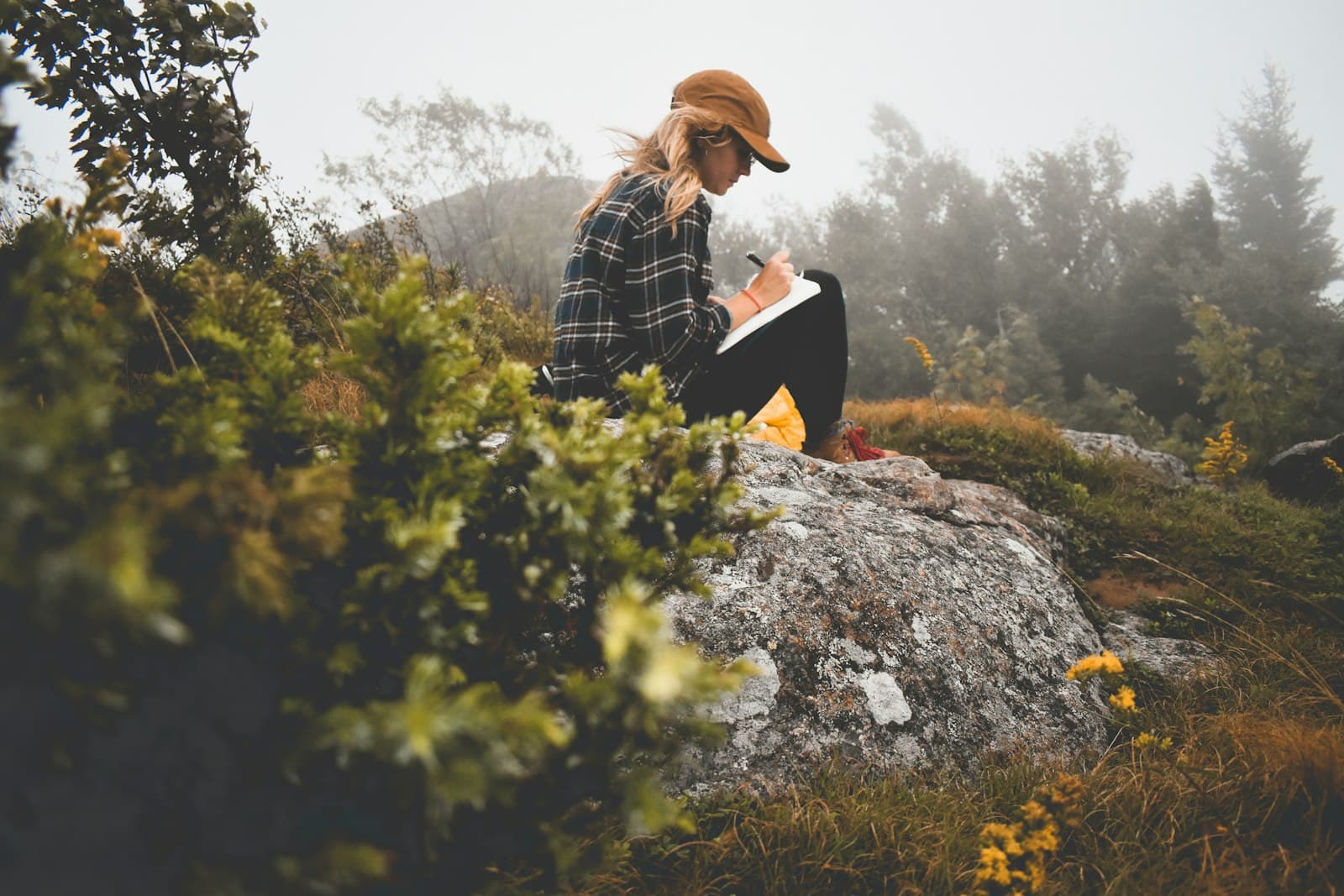 Persona meditando tranquilamente en la naturaleza con un diario cerca