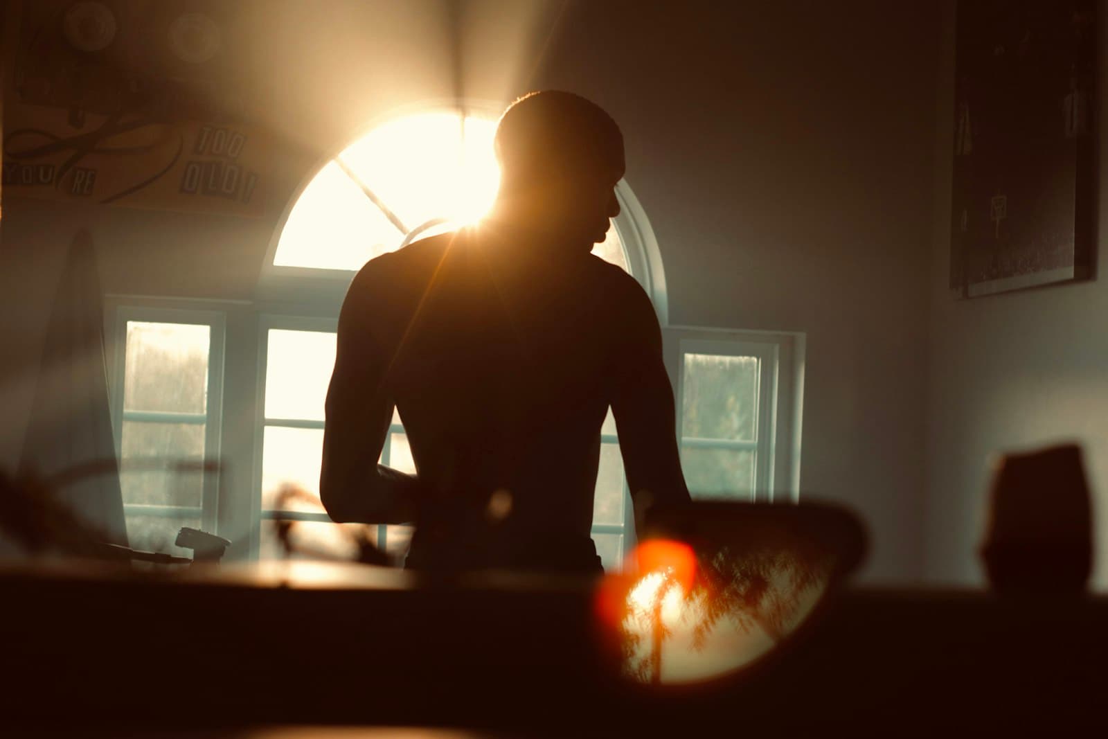 Una persona sentada en posición de meditación cerca de una ventana, con luz suave.
