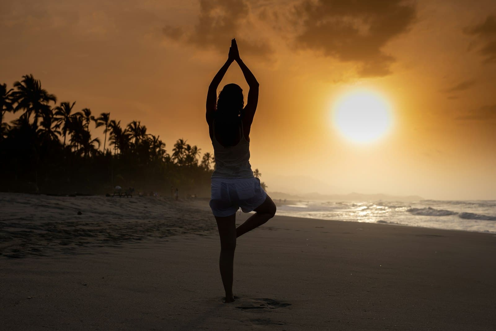 Una mujer practicando yoga al atardecer, con una postura serena y conectada