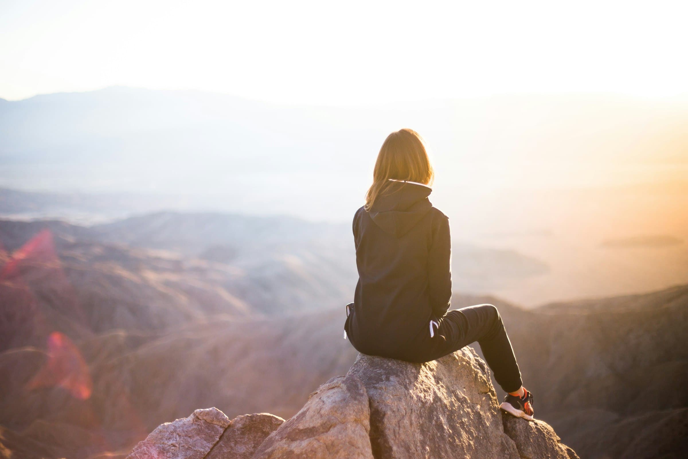 Una mujer meditando tranquilamente al amanecer en un entorno natural exuberante.