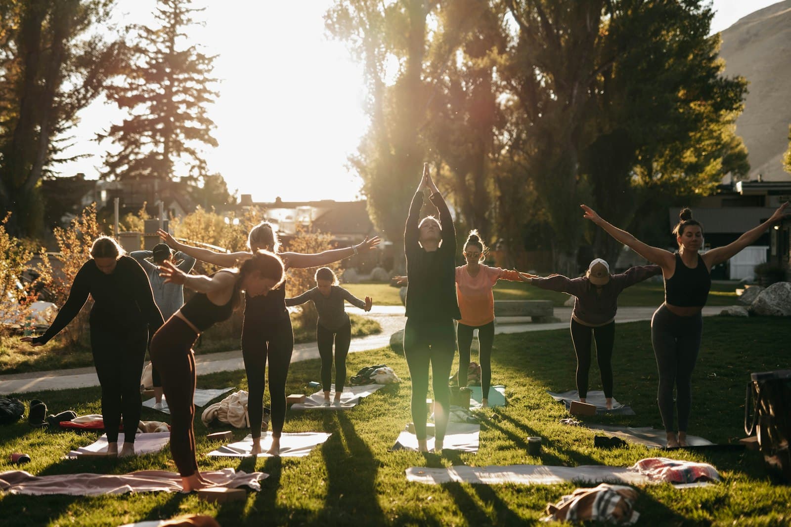 Un grupo diverso de personas practicando yoga al aire libre, con instructor, en un retiro sereno.