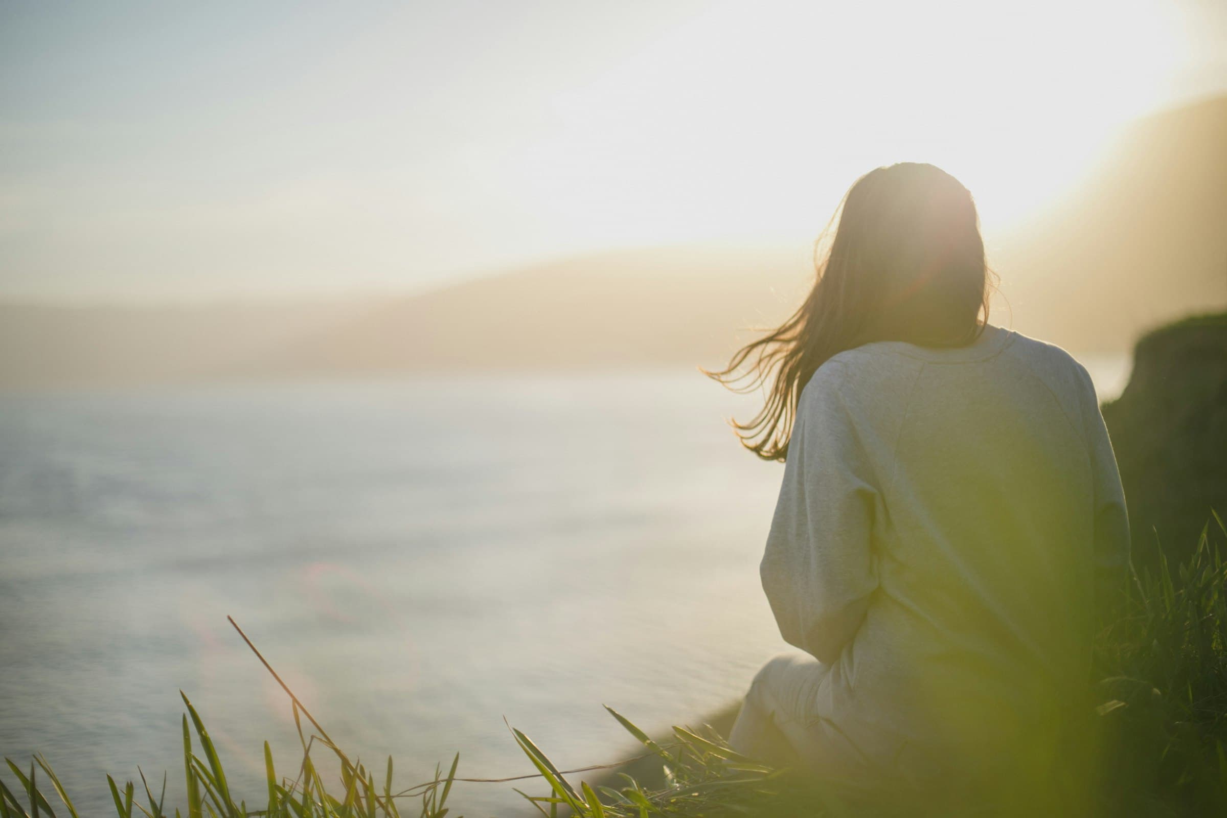 Mujer meditando serenamente frente al océano al atardecer