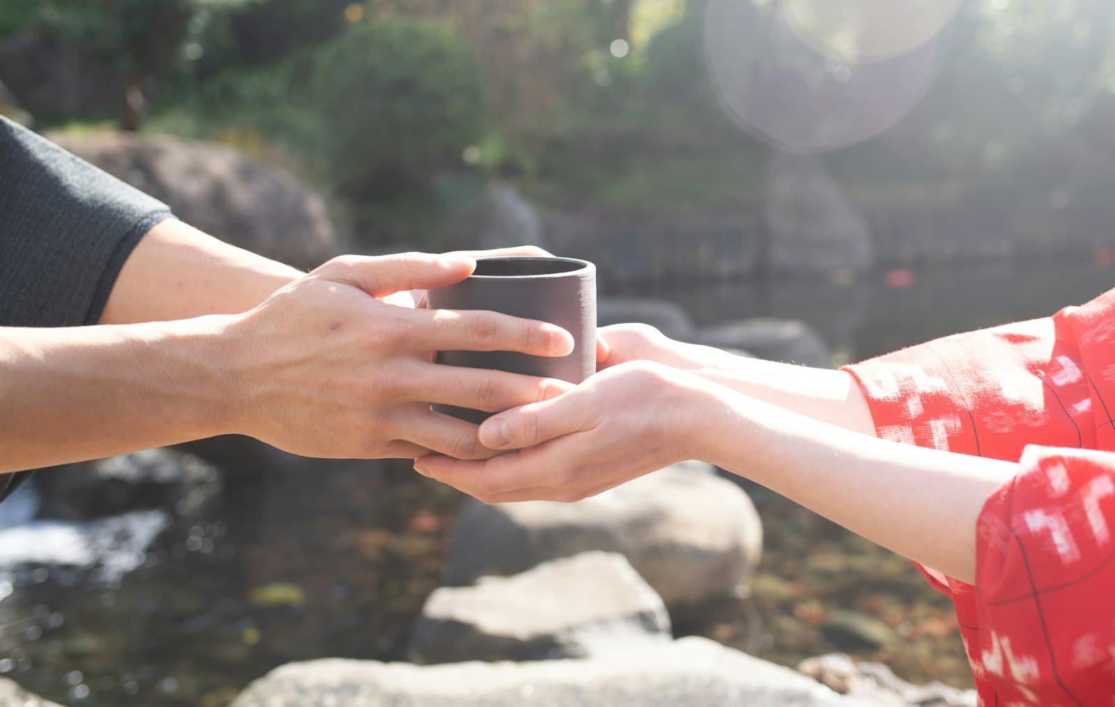 Manos sosteniendo una taza de té caliente bajo la luz del sol