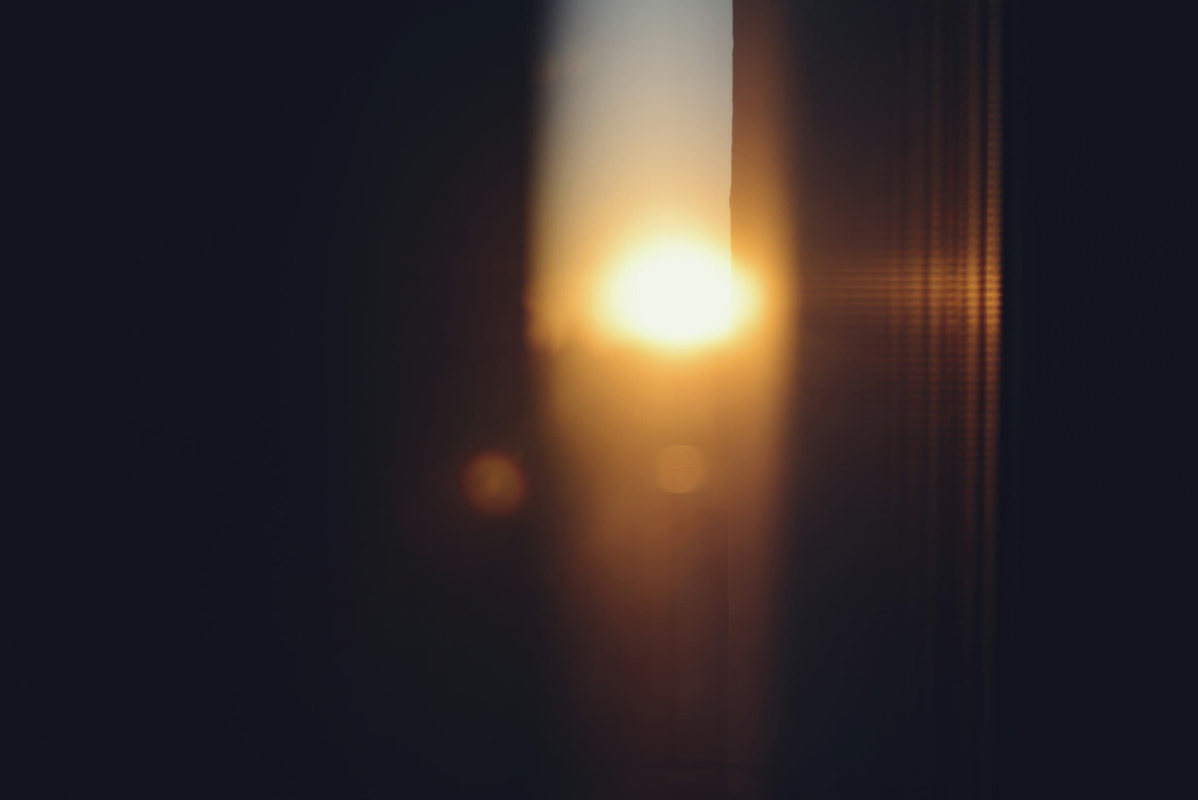 Persona meditando tranquilamente al amanecer, con luz suave entrando por una ventana