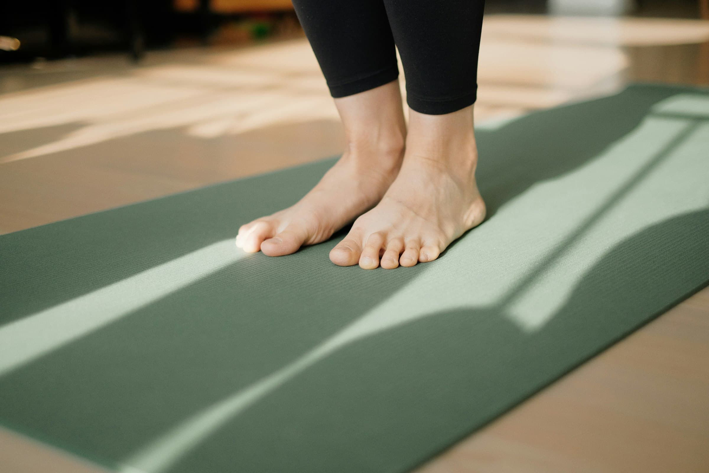 Una mujer practicando yoga suavemente al amanecer, con luz dorada llenando la habitación