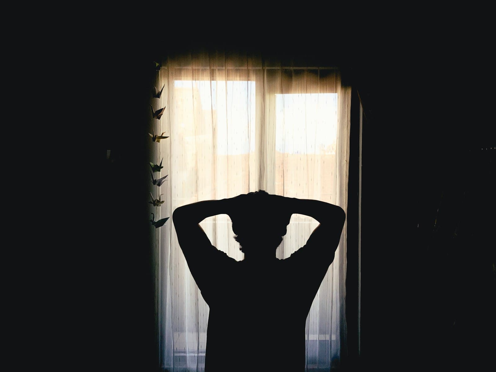 Una persona meditando tranquilamente junto a una ventana con luz matutina suave.