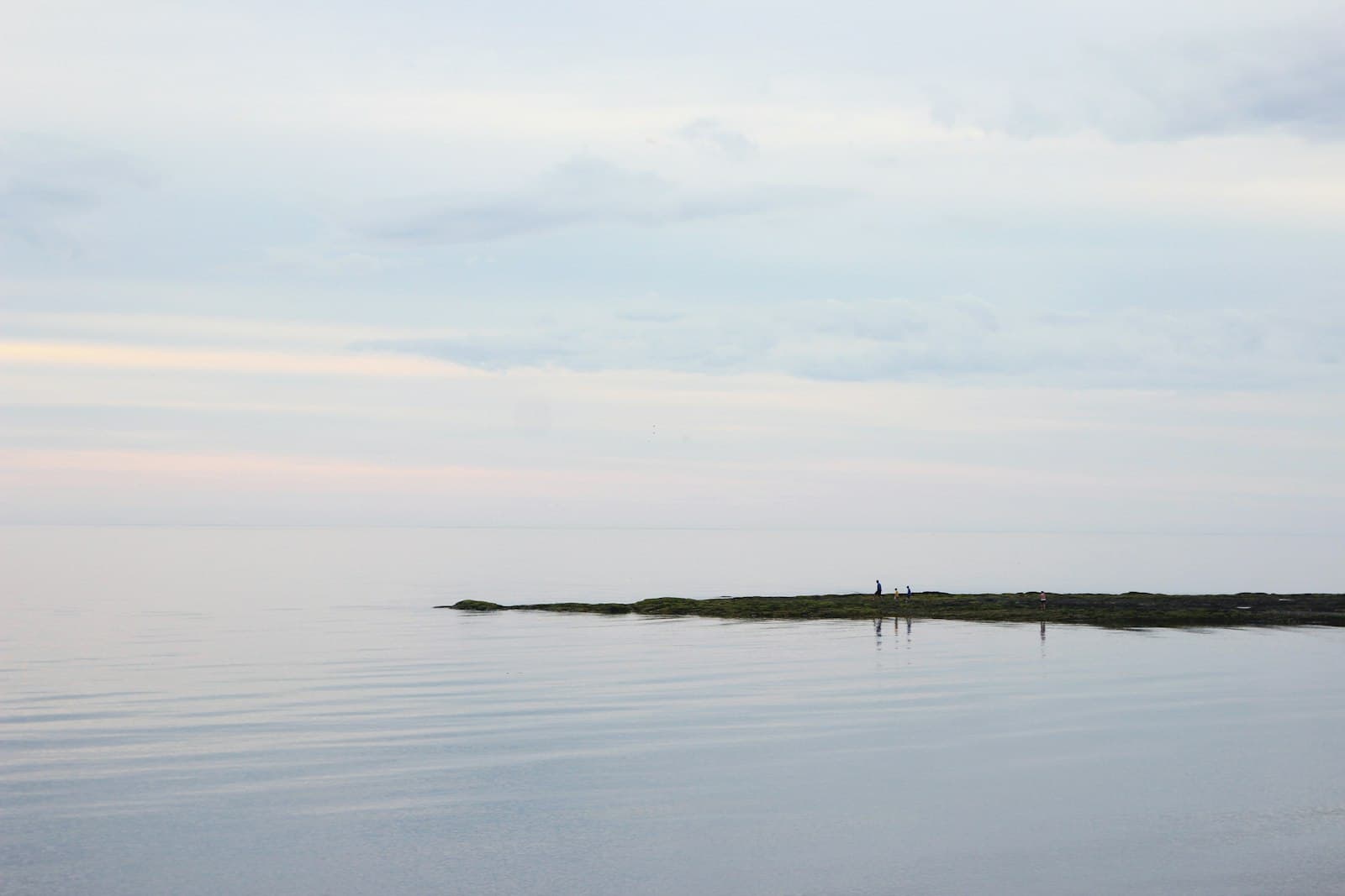 Una persona meditando tranquilamente junto a un lago al atardecer, con colores cálidos en el cielo.