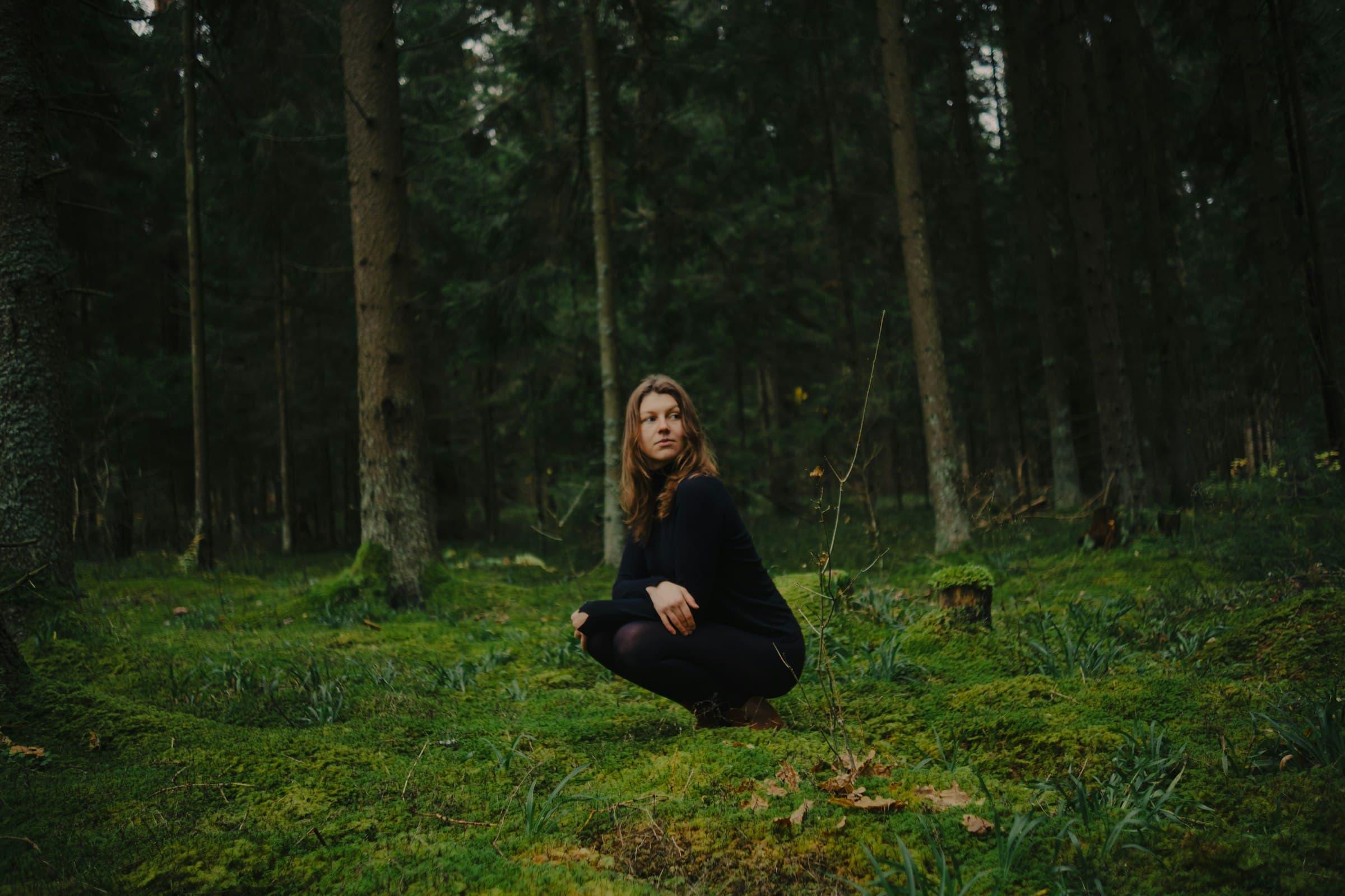 Mujer meditando serenamente en medio de un bosque verde, con los ojos cerrados