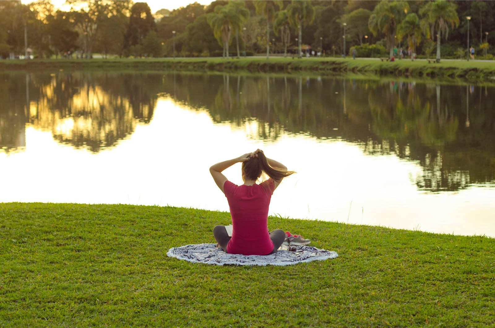 Una mujer sentada tranquilamente junto a un lago, observando el paisaje con reflexión
