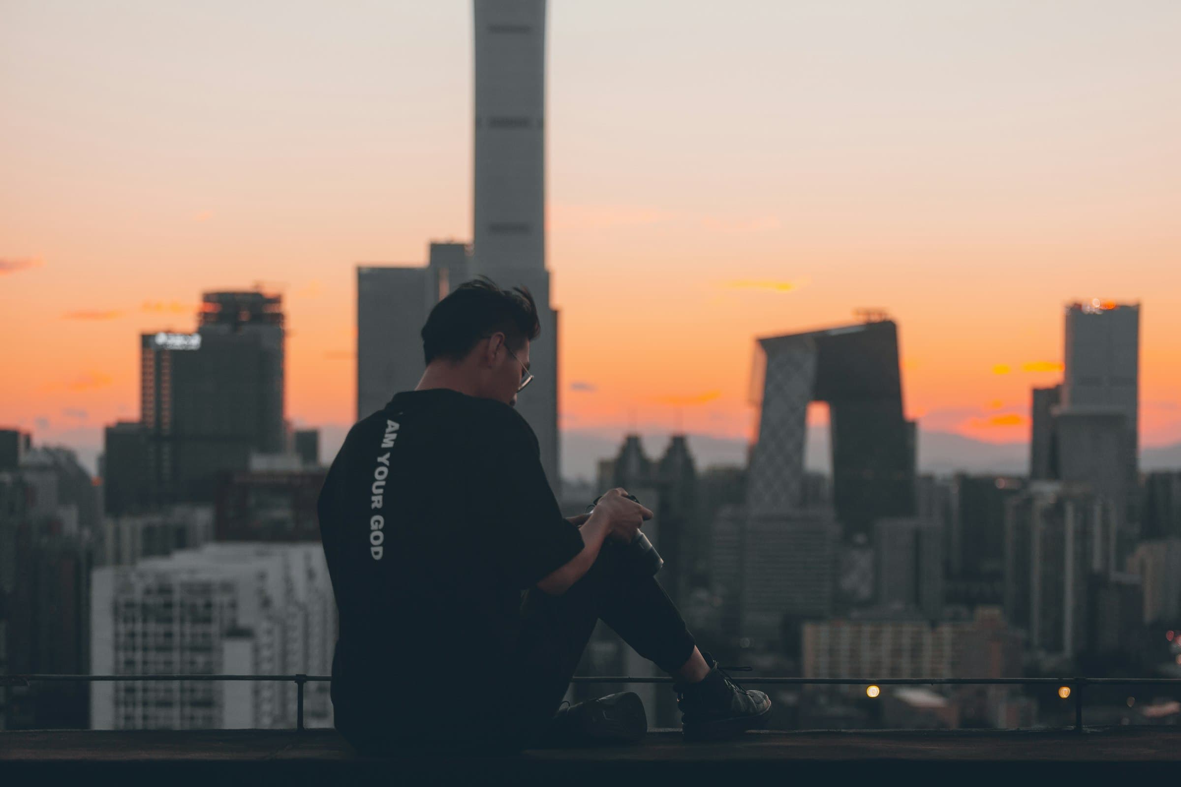 Persona meditando en una azotea urbana al amanecer, con la ciudad despertando a lo lejos