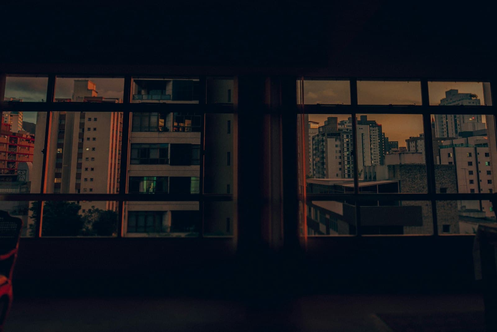 Una persona bebiendo café pensativamente, mirando por la ventana en un apartamento de la ciudad, con luz suave