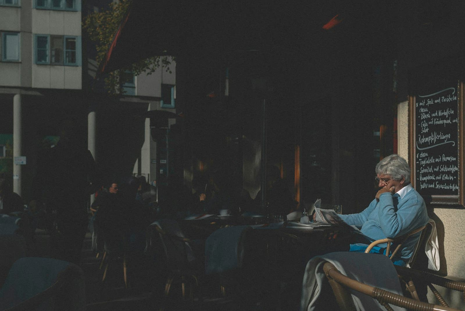 Una mujer bebiendo café con atención plena en una cafetería urbana bulliciosa, con la luz de la mañana.