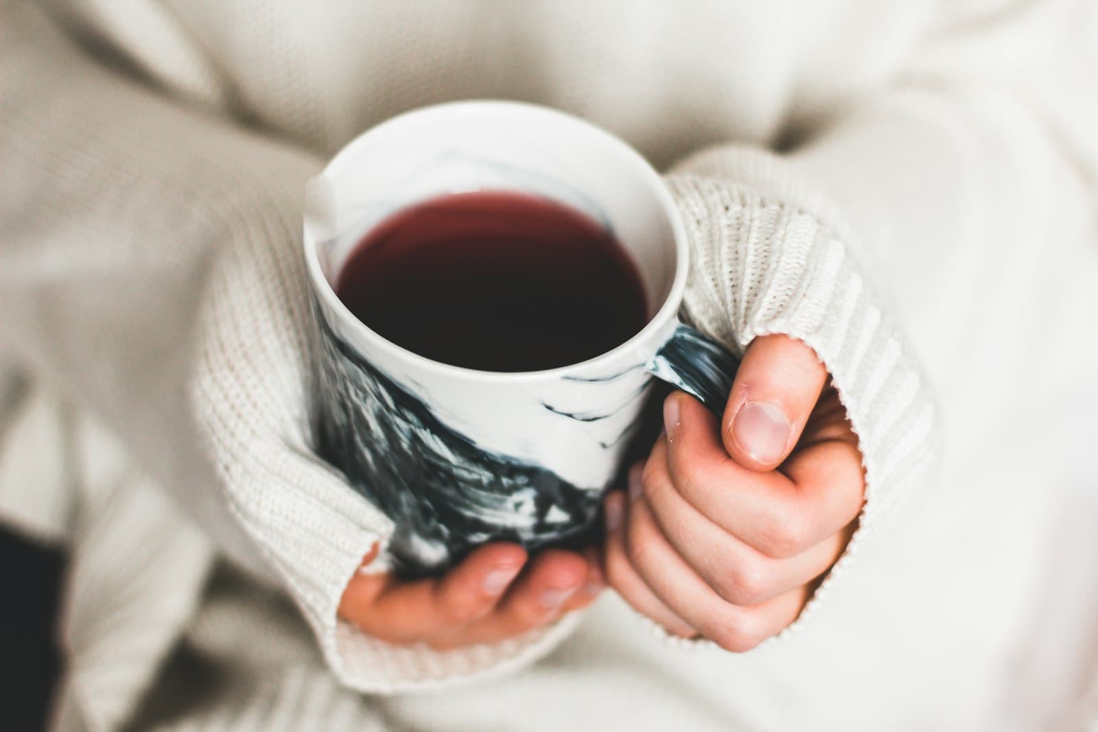 Manos sosteniendo una taza de té caliente, en un momento de reflexión tranquila