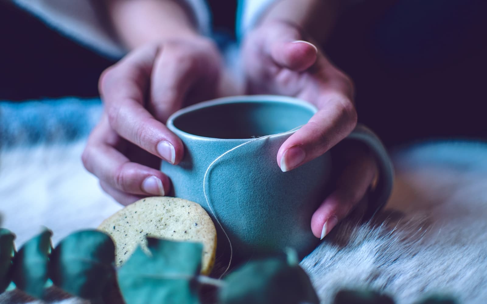 Manos sosteniendo una taza de té humeante con delicadeza