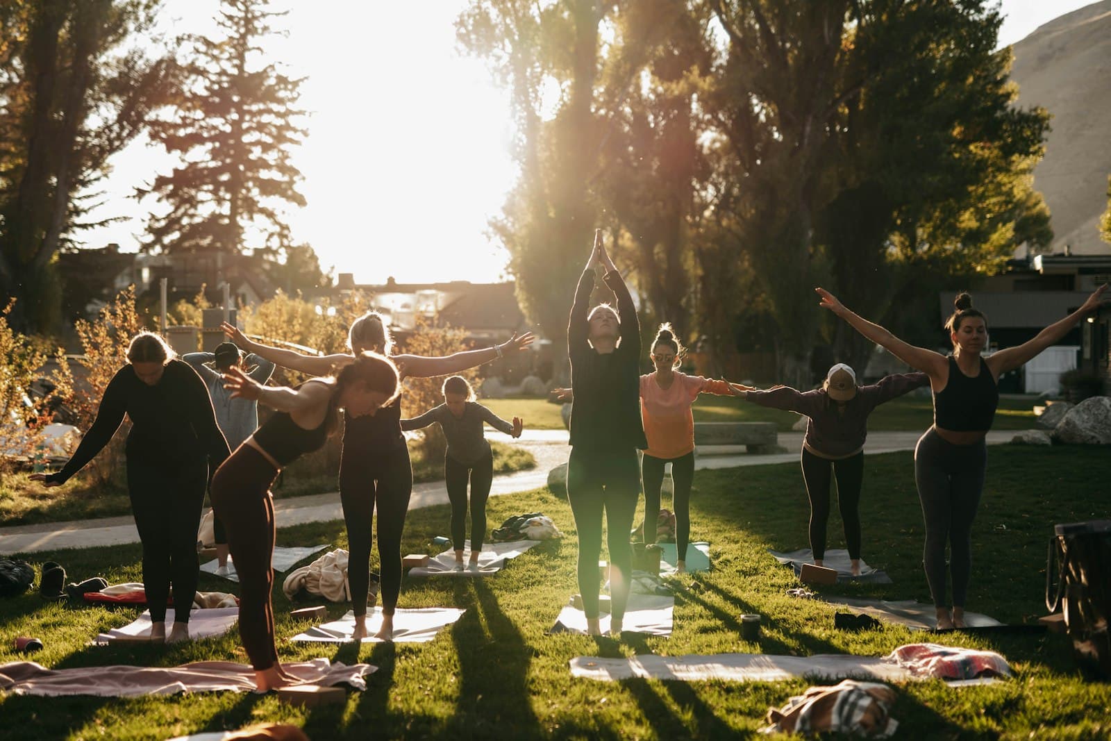 Un grupo diverso de personas meditando al aire libre en un entorno sereno, evocando un retiro de bienestar.