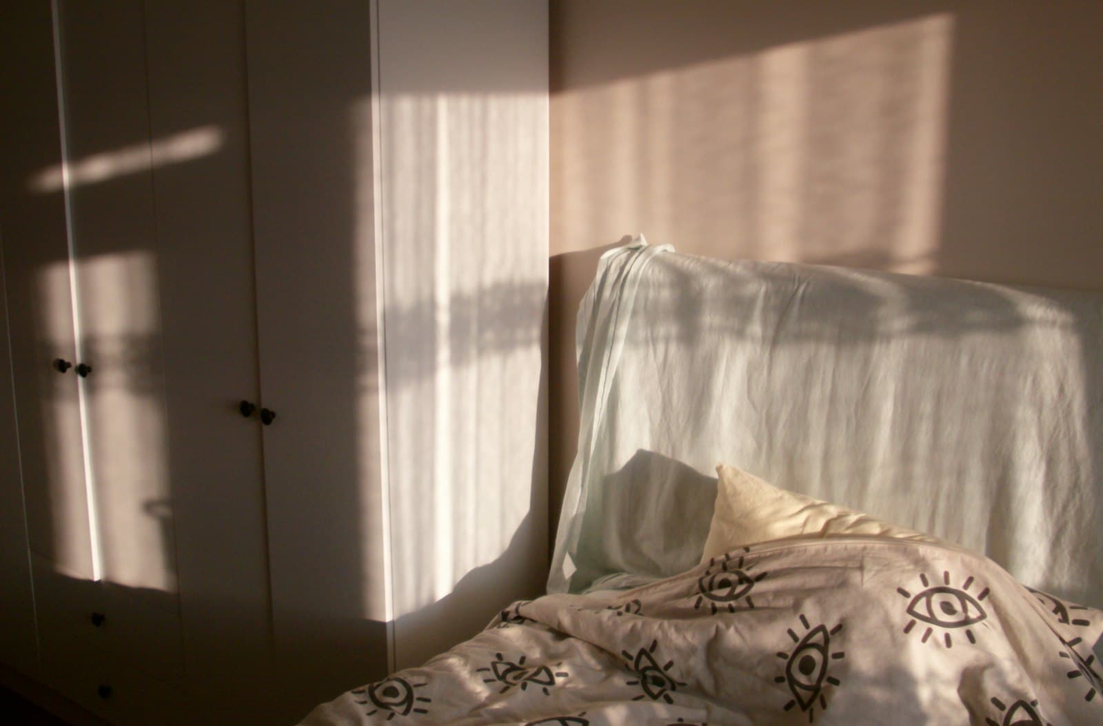 Luz solar entrando por una ventana a una habitación, iluminando suavemente una cama en un dormitorio tranquilo.