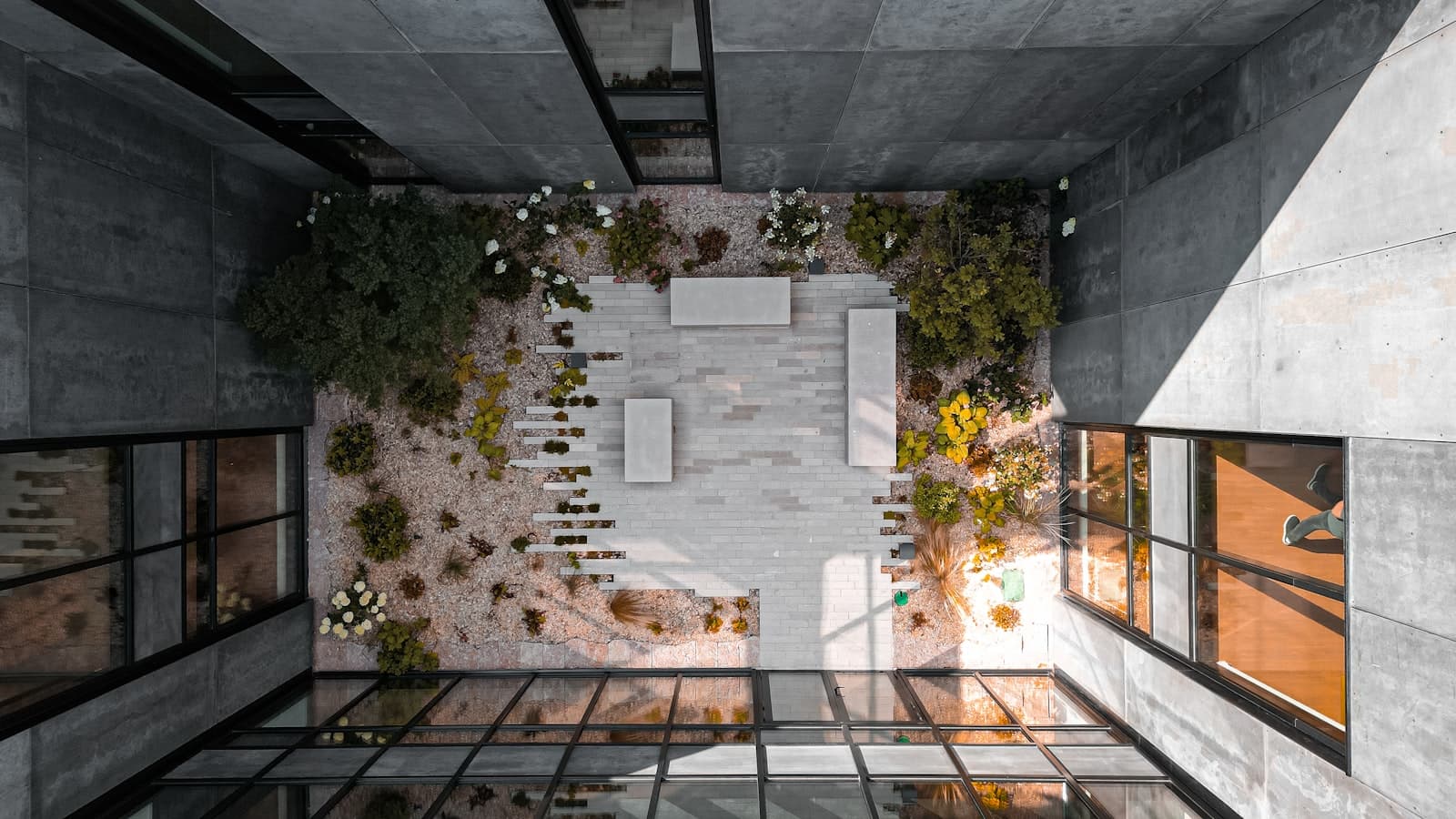 Patio interior con plantas exuberantes y piedra natural en una casa moderna, difuminando los límites entre interior y exterior.