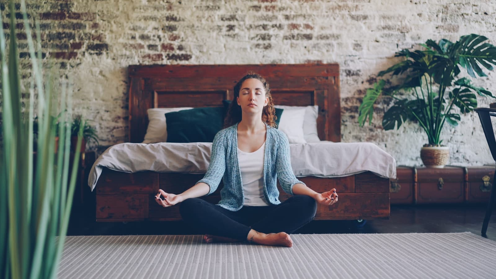 Una persona estirándose suavemente o meditando en un dormitorio tranquilo al amanecer