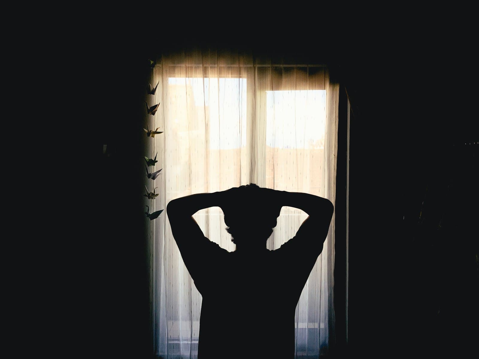 Persona estirándose suavemente al lado de una ventana con luz matutina