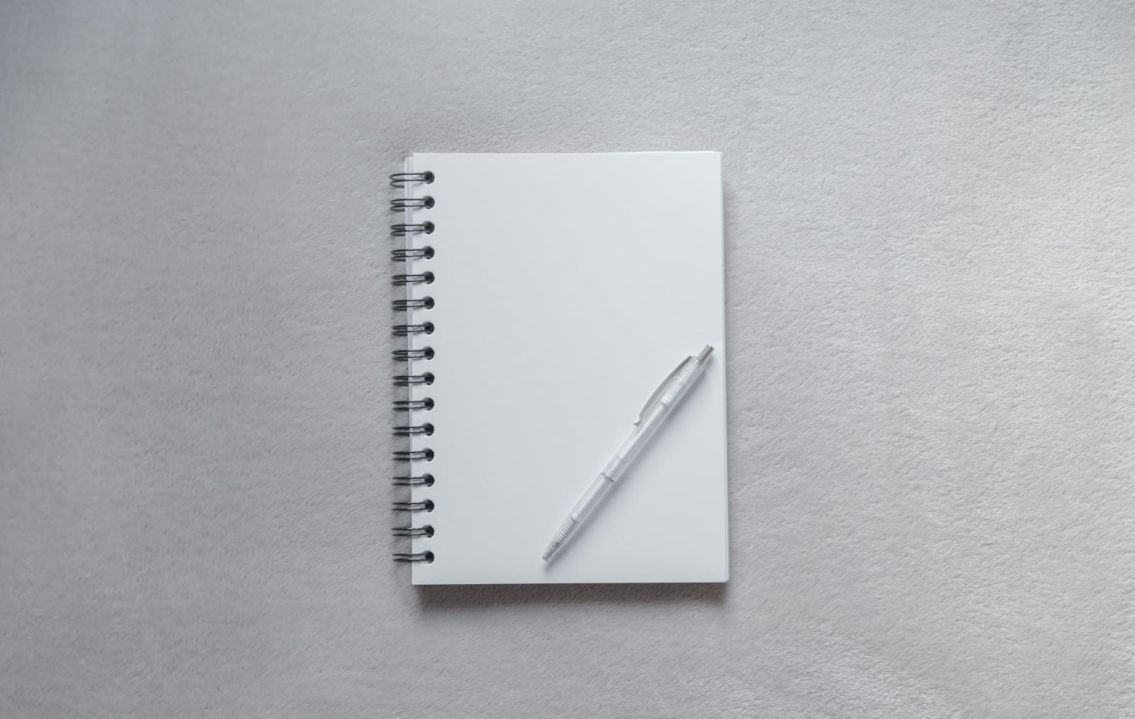 An open notebook with a pen on a wooden surface, bathed in morning light