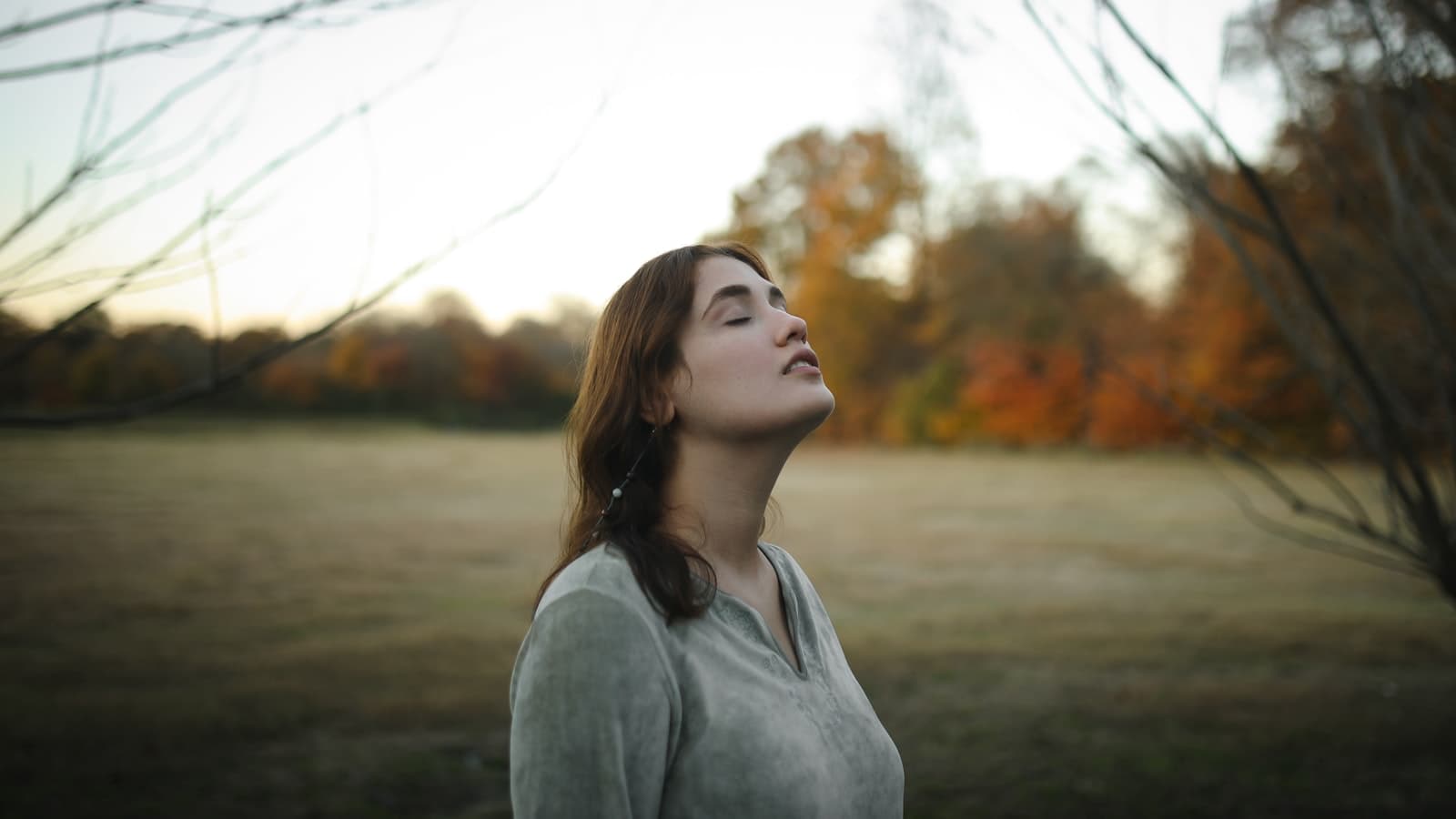 Una mujer respirando profundamente al aire libre, con el pecho y el diafragma expandiéndose suavemente.