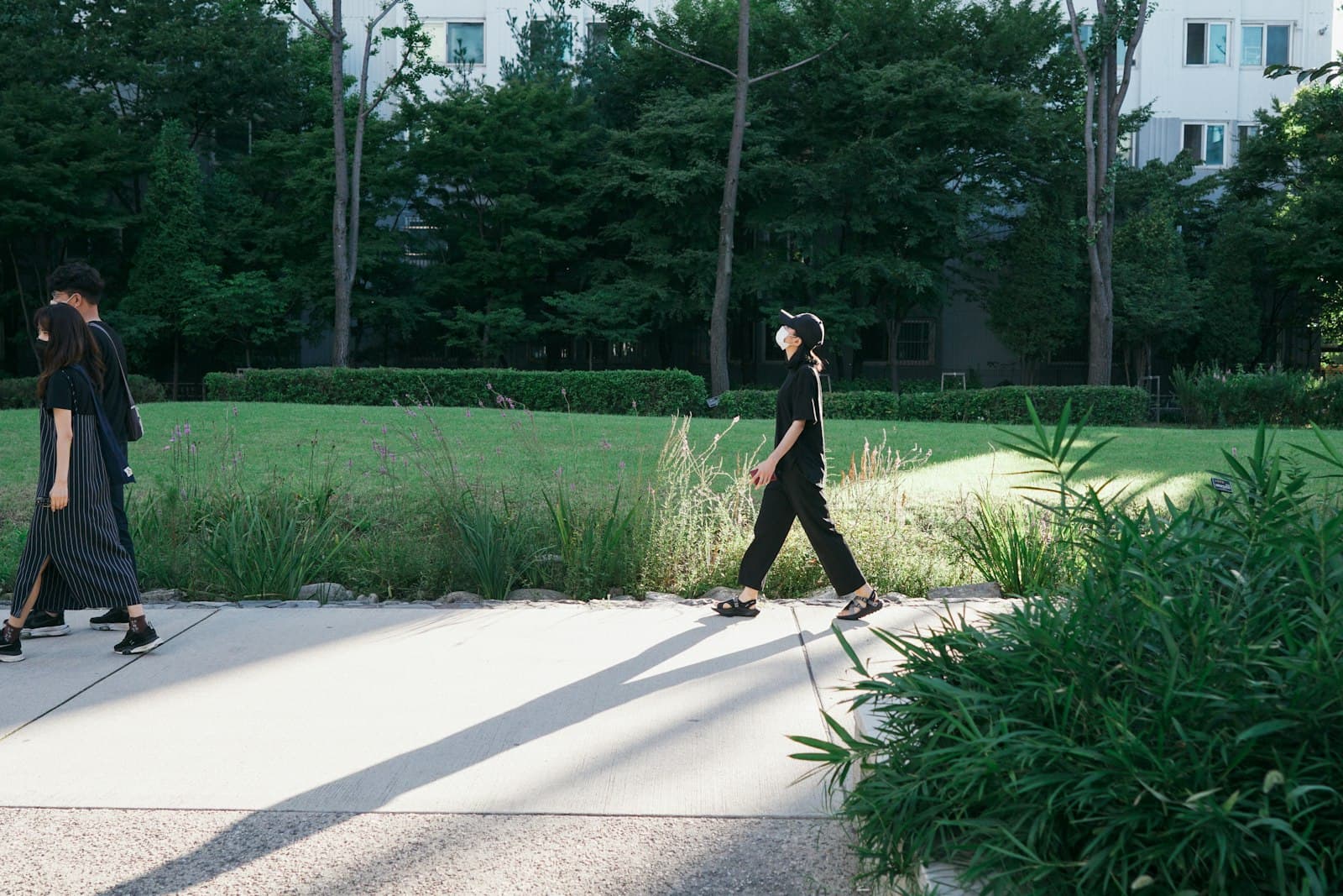 Una persona caminando tranquilamente por un parque de la ciudad con auriculares, observando la naturaleza